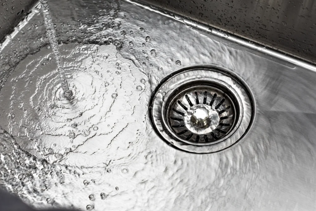 Water flowing down a kitchen sink drain into garbage disposal